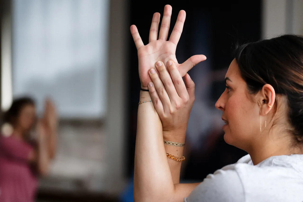 Students in a studio with hands raised during a class